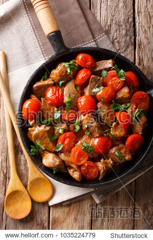 stewed beef in spicy sauce with tomatoes and greens close-up on