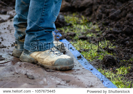 Closeup of work boots on tarp next to soil