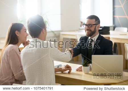 Smiling lawyer realtor or financial advisor handshaking young couple thanking for advice insurance broker or bank worker and millennial customers shake hands making deal investment or taking loan