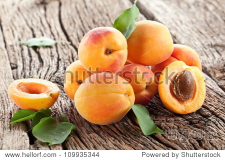 apricots with leaves on the old wooden table.