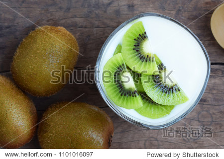 kiwi slices on yogurt with kiwi fruits and spoon on wooden