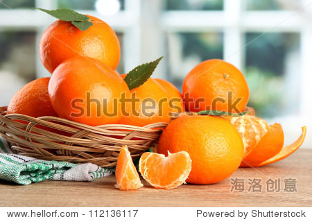 tangerines with leaves in a beautiful basket, on wooden table on