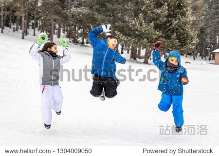 Three kids jumping together in a snowy field