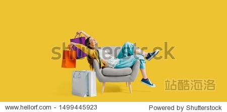 Cheerful happy shopaholic woman with lots of shopping bags she is sitting on an armchair and celebrating blank copy space