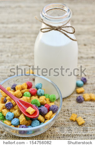 a glass bottle of milk and a bowl of cereal on a fabric t