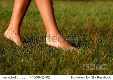 close-up of female legs walking on green grass barefoot