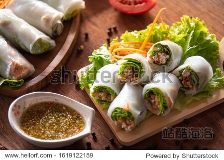 Asian spring rolls as portion stuff vegetable pork inside noodle tubes on old wood plate with spicy sauce