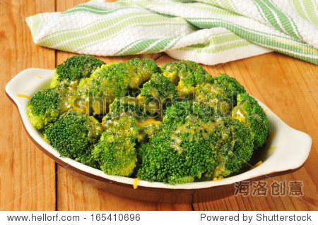 a small casserole dish of steamed broccoli topped with cheddar