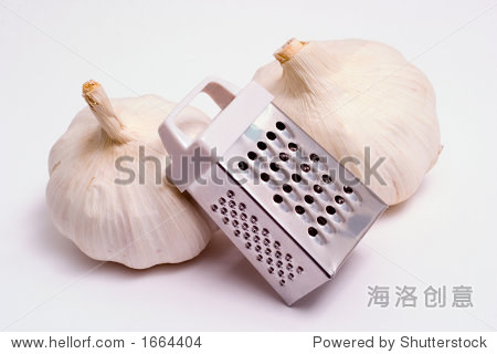an isolated stainless steel grater with two heads of garlics