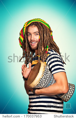 portrait of a rastafarian guy playing his drum.