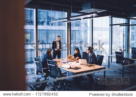 From above of group of diverse colleagues in formal clothing discussing business ideas while gathering at table in modern office and working together