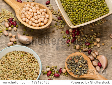 various legumes in wooden spoon and bowl on old wooden back