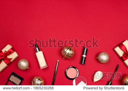 Makeup professional products flat lay on red background top view copy space. Foundation eyeshadows blusher sponge mascara lipstick gift. Christmas cosmetic. Christmas shopping. Xmas celebration