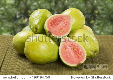 a brazilian guava cut in a half in front of some entire guavas