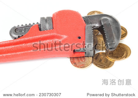 monkey wrench on a heap of gold coins isolated on white back