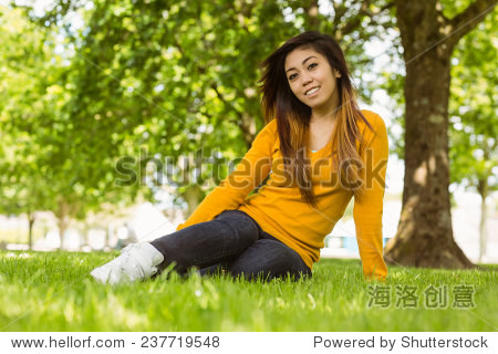 portrait of beautiful relaxed young woman sitting on grass at