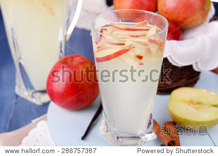 glass and carafe of apple cider with fruits and spices on table
