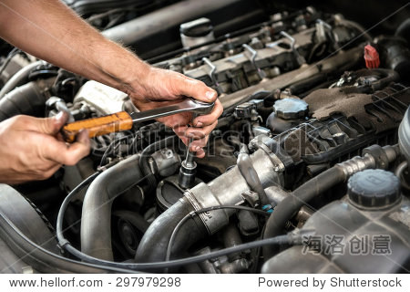mechanic using a wrench and socket on the engine of a motor car