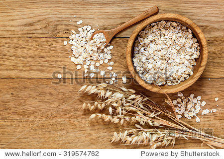 rolled oats and oat ears of grain on a wooden table, copy space
