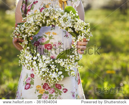 little girl holding wreath from lily of the valley in her hands