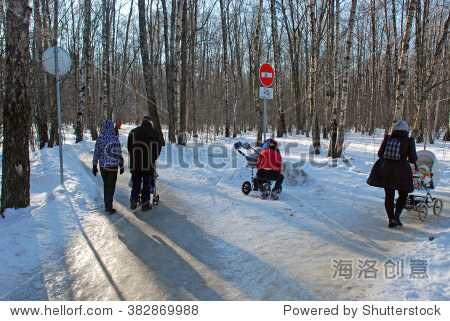 Three families with small children in strollers meet at a crossroads in Moscow park