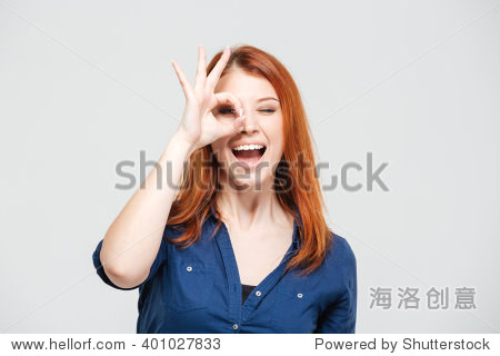 happy excited redhead young woman looking through hole made of
