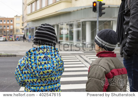 and adult waiting at pedestrian crossing for green light