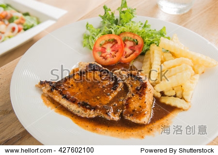 pork steak in white plate,glass of water,french fries placed on