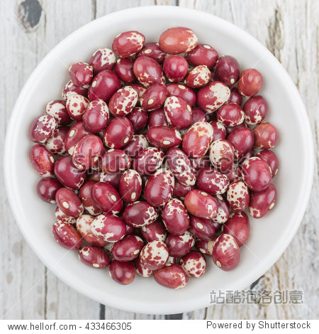 pinto beans or speckled beans in white bowl over wooden back