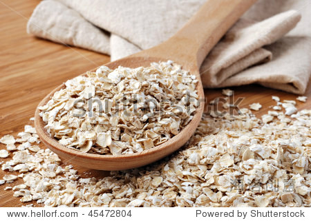 whole grain rolled oats with wooden spoon and homespun napkin.