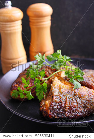 fried fish on a black plate decorated with fresh parsley on a