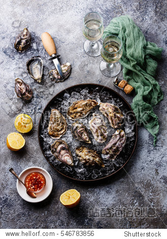 oysters in plate with spicy sauce and champagne on stone texture