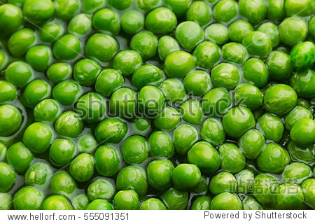 wet fresh green peas in water closeup as background.