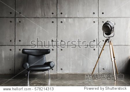 Loft interior mock up photo. Grey block wall with leather black chair and vintage light source lamp. Background photo with copy space for text.