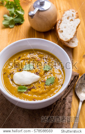 bowl of spicy carrot and lentil soup on a wooden table - 站酷