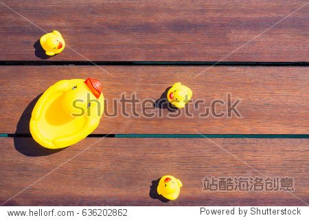 rubber toy mother duck with childs on wooden background top view