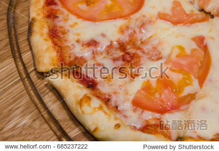hot piece of pizza with melted cheese on a rustic wooden table.