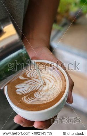 professional barista pouring a milk to cup of coffee latte with