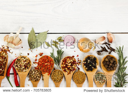different spices in wooden spoon on light wooden background.