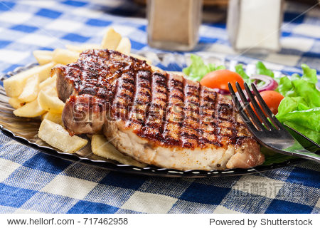 grilled pork chop served with french fries and salad - 图片素材
