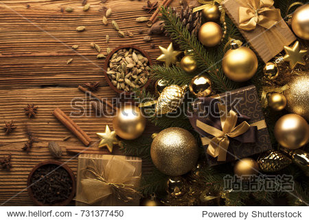Christmas decoration in golden and brownish aesthetics with presents in boxes golden baubles christmas spices all on a rustic wooden background with copy space.