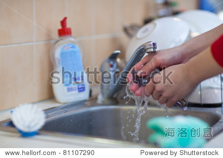 washing of the dishes - woman hands rinsing dishes under running