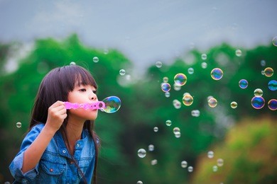 asian little girl is blowing a soap bubbles