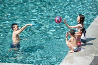 happy asian family playing in the pool