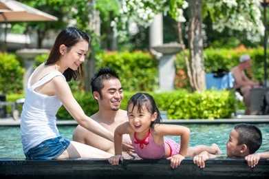 happy asian family playing in the pool