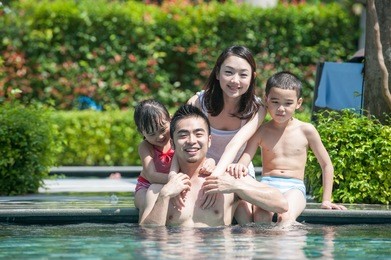 happy asian family playing in the pool