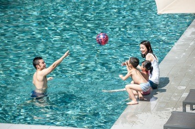 happy asian family playing in the pool