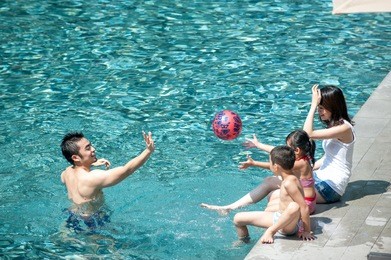 happy asian family playing in the pool