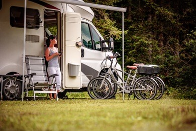 woman is standing with a mug of coffee near the camper. caravan car vacation. family vacation travel, holiday trip in motorhome rv