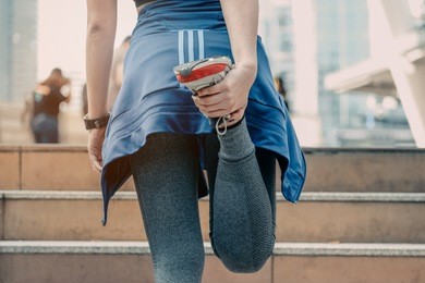 a men athlete doing warming stretching in the city street. tight sport clothes. urban workout.